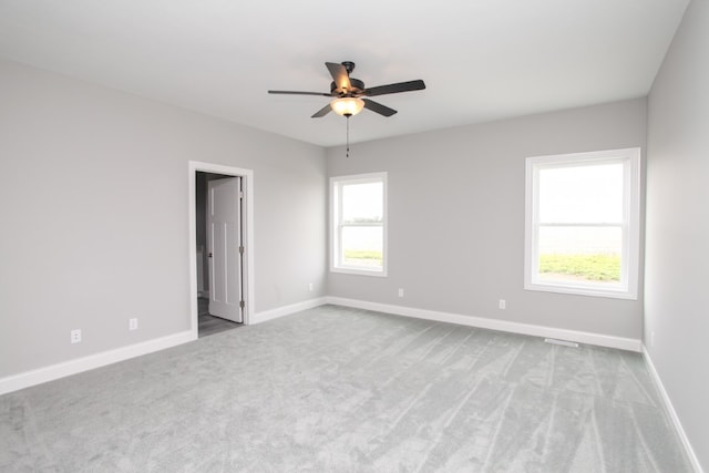 empty room with ceiling fan, plenty of natural light, and light colored carpet