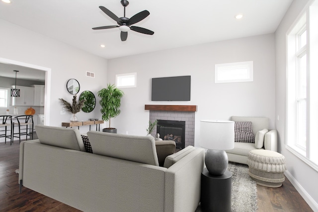 living room featuring a fireplace, plenty of natural light, ceiling fan, and dark hardwood / wood-style flooring