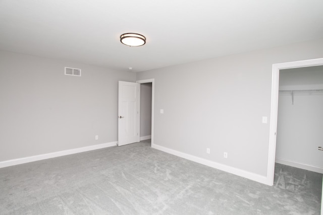 unfurnished bedroom featuring a walk in closet, carpet flooring, and a closet