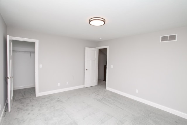 unfurnished bedroom with light colored carpet, a closet, and a walk in closet