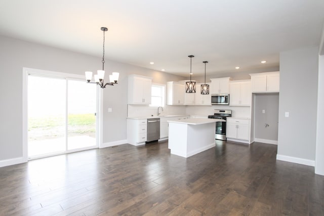 kitchen featuring appliances with stainless steel finishes, plenty of natural light, pendant lighting, and dark wood-type flooring