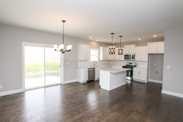 kitchen featuring appliances with stainless steel finishes, a center island, dark wood-type flooring, and hanging light fixtures