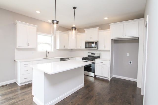 kitchen featuring dark hardwood / wood-style flooring, white cabinetry, appliances with stainless steel finishes, sink, and a center island