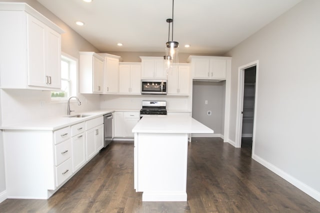 kitchen with appliances with stainless steel finishes, sink, white cabinets, a kitchen island, and dark wood-type flooring