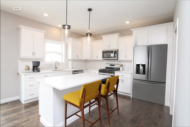 kitchen with dark hardwood / wood-style floors, a kitchen island, white cabinets, appliances with stainless steel finishes, and sink