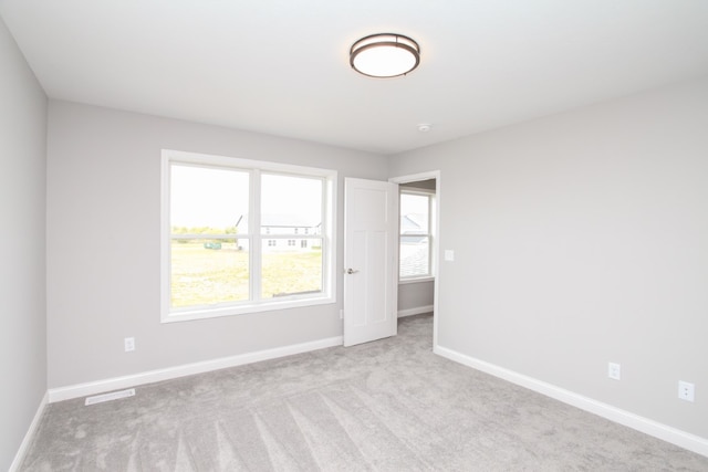 unfurnished room featuring light colored carpet and a healthy amount of sunlight