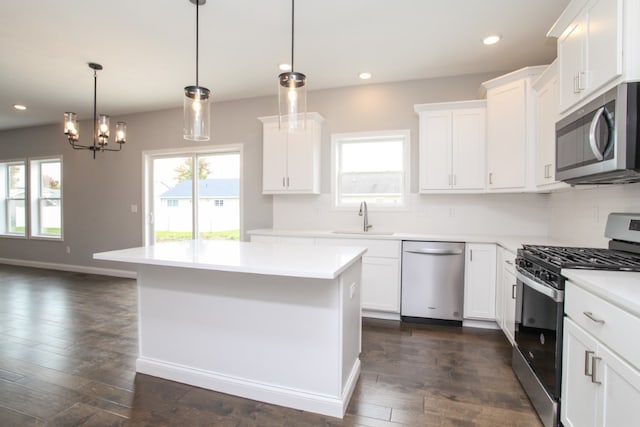 kitchen with sink, stainless steel appliances, pendant lighting, and dark wood-type flooring