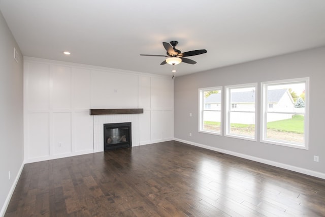 unfurnished living room featuring dark hardwood / wood-style flooring, a tile fireplace, and ceiling fan