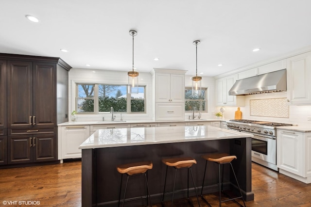 kitchen with sink, wall chimney range hood, double oven range, and a center island