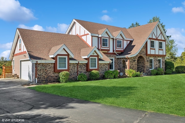 tudor house featuring a garage and a front lawn