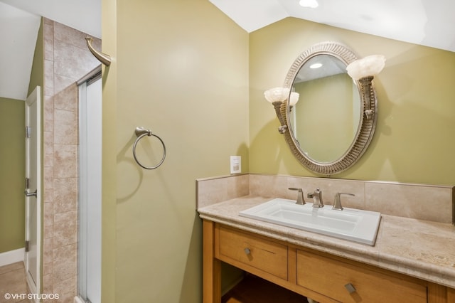 bathroom with walk in shower, vanity, and lofted ceiling