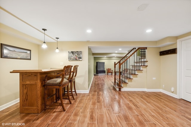 bar featuring light hardwood / wood-style flooring and hanging light fixtures