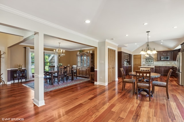 dining area featuring an inviting chandelier, lofted ceiling, ornamental molding, and hardwood / wood-style flooring