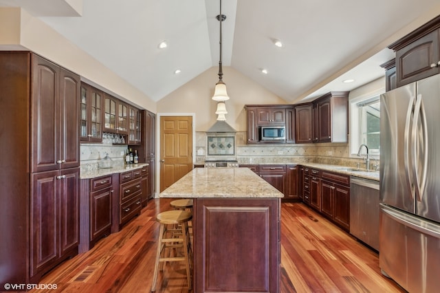 kitchen featuring pendant lighting, a kitchen island, backsplash, hardwood / wood-style flooring, and stainless steel appliances