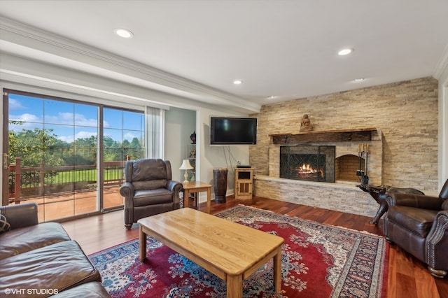 living room featuring wood-type flooring, a stone fireplace, and ornamental molding