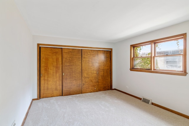 unfurnished bedroom featuring light colored carpet and a closet