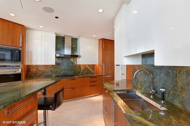 kitchen with stainless steel oven, black microwave, tasteful backsplash, and wall chimney exhaust hood