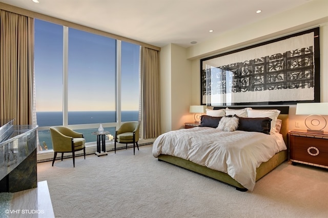 carpeted bedroom with floor to ceiling windows and a water view