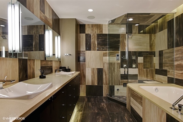 bathroom featuring dual sinks, tile walls, large vanity, and independent shower and bath