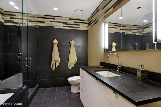 bathroom featuring tile flooring, tile walls, a shower with door, large vanity, and toilet