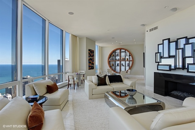 living room with expansive windows, a water view, and a healthy amount of sunlight