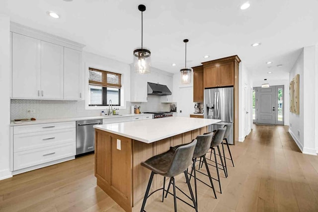 kitchen featuring a center island, stainless steel appliances, light hardwood / wood-style flooring, and a healthy amount of sunlight