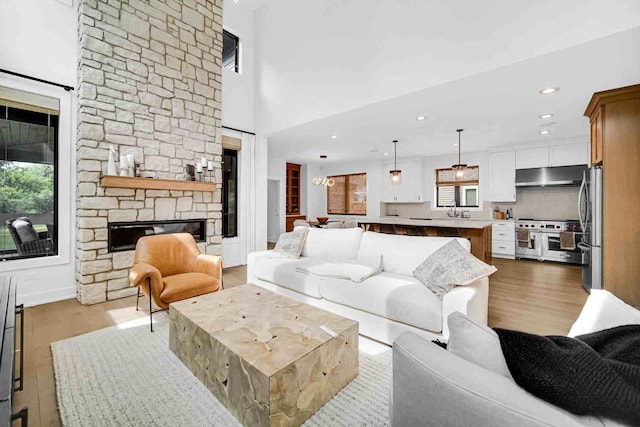 living room with a stone fireplace, light hardwood / wood-style flooring, and a wealth of natural light