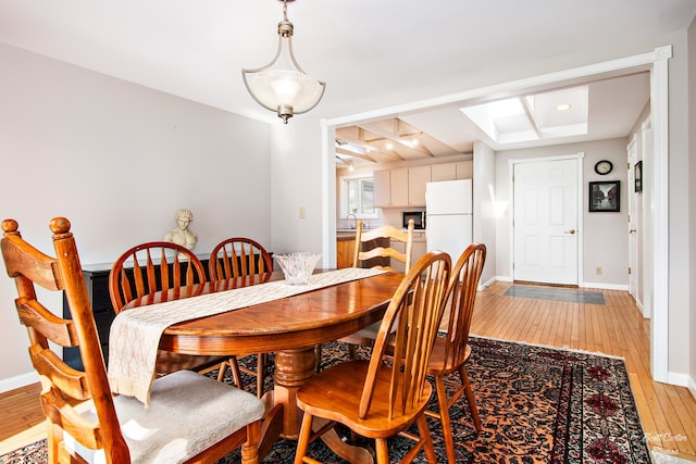 dining area featuring light wood-type flooring, sink, and a skylight