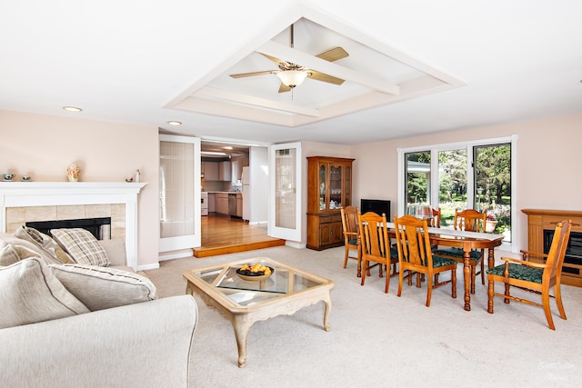 interior space featuring ceiling fan, light hardwood / wood-style flooring, a raised ceiling, and a tiled fireplace