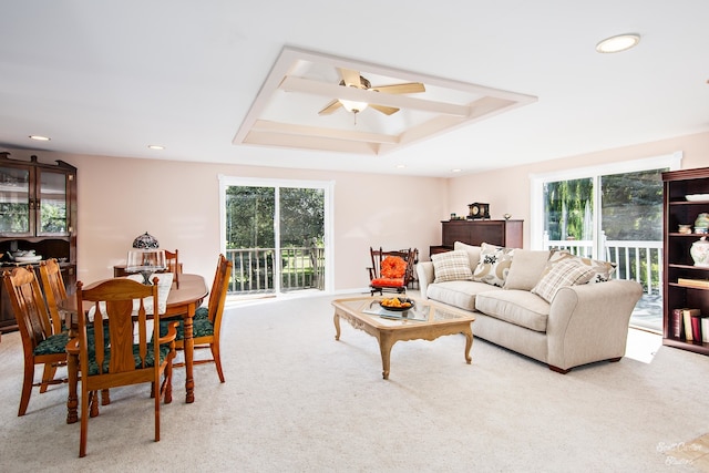 living room with ceiling fan, a raised ceiling, light colored carpet, and plenty of natural light