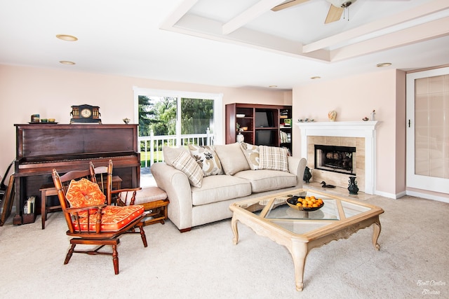 living room with beamed ceiling, a tiled fireplace, light colored carpet, and ceiling fan