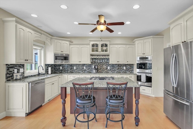 3001 E Stone Creek Blvd, Urbana, IL 61802 - kitchen with stainless steel appliances, a ceiling fan, a breakfast bar area, backsplash, and light wood finished floors