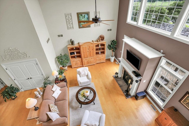 3001 E Stone Creek Blvd, Urbana, IL 61802 - living room featuring a high ceiling, light wood finished floors, a glass covered fireplace, and ceiling fan