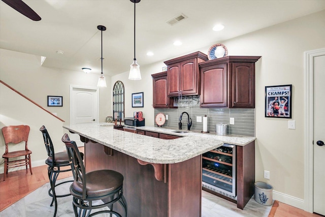 3001 E Stone Creek Blvd, Urbana, IL 61802 - kitchen featuring beverage cooler, decorative backsplash, a kitchen bar, stainless steel microwave, and light stone countertops