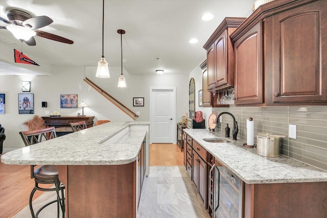 3001 E Stone Creek Blvd, Urbana, IL 61802 - kitchen with beverage cooler, a kitchen bar, tasteful backsplash, a ceiling fan, and light stone countertops
