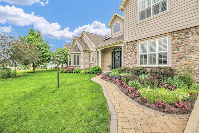 3001 E Stone Creek Blvd, Urbana, IL 61802 - view of front of property with stone siding, a front yard, and roof with shingles