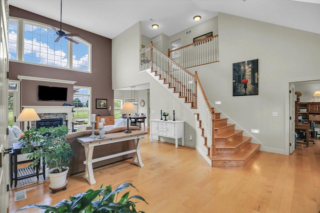 3001 E Stone Creek Blvd, Urbana, IL 61802 - living area featuring high vaulted ceiling, ceiling fan, wood finished floors, stairs, and a stone fireplace