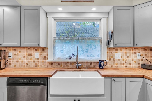 kitchen featuring butcher block countertops, stainless steel dishwasher, and a sink
