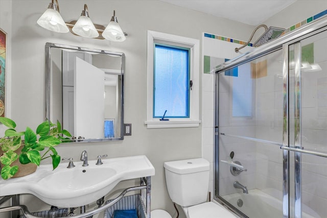 bathroom with plenty of natural light, a sink, toilet, and combined bath / shower with glass door