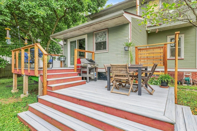 wooden deck with outdoor dining space and area for grilling