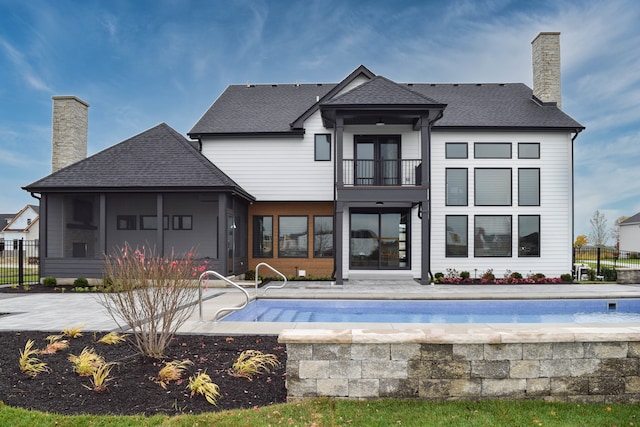 rear view of property featuring a balcony and a fenced in pool