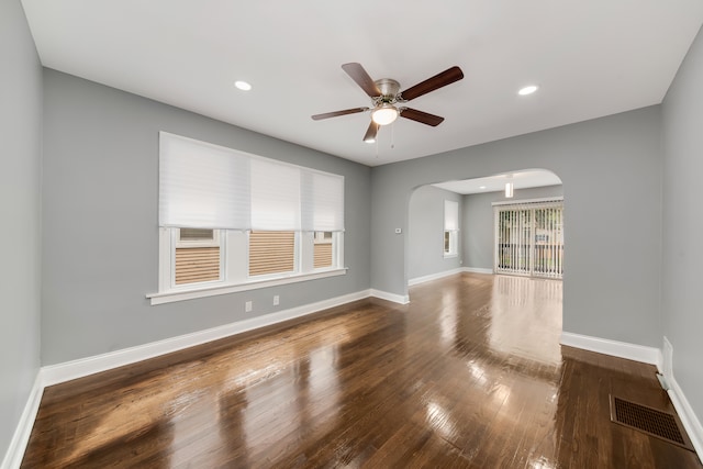 spare room featuring a wealth of natural light, ceiling fan, and dark wood-type flooring