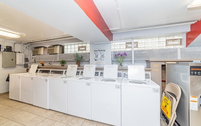 laundry room with light tile patterned floors, washing machine and clothes dryer, water heater, and electric panel