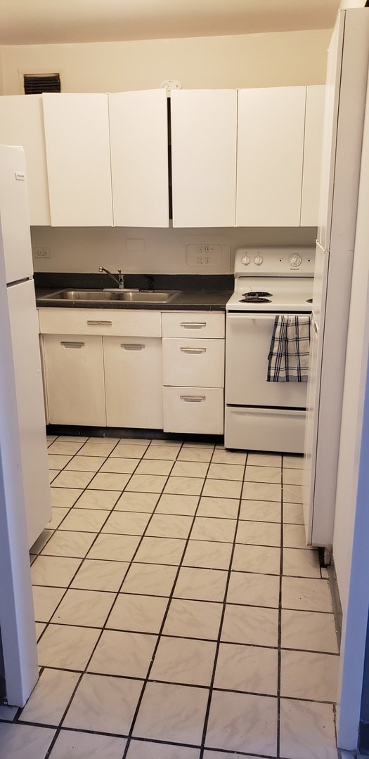 kitchen featuring white cabinetry, light tile patterned flooring, and white appliances