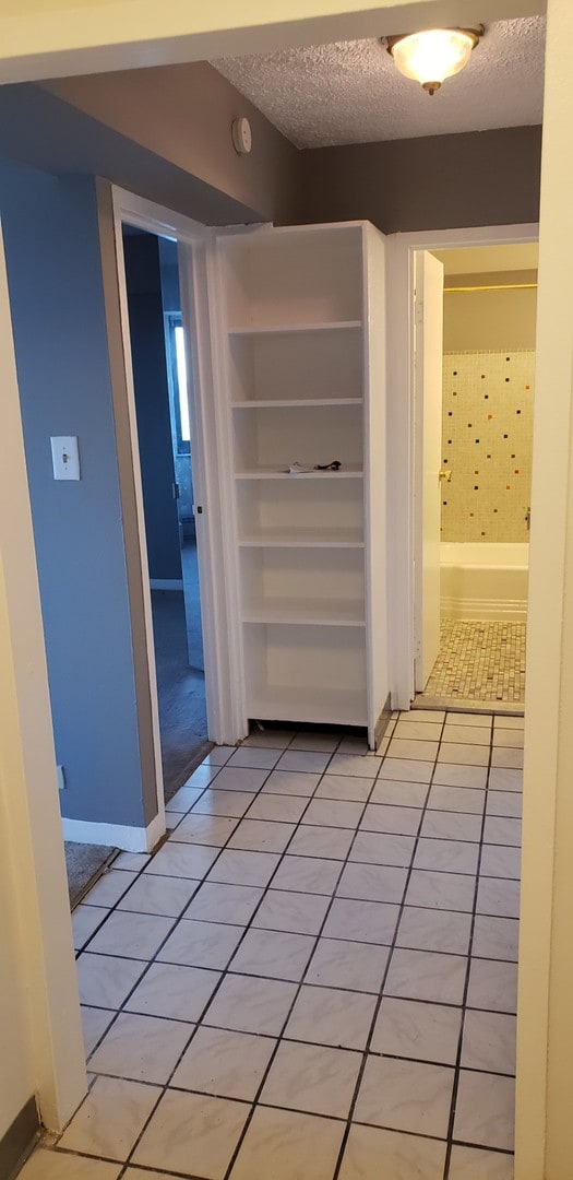 hallway featuring light tile patterned floors and a textured ceiling