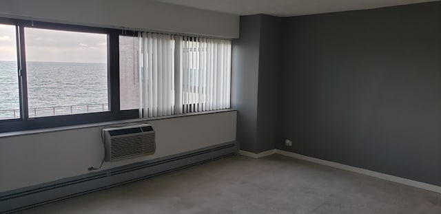 carpeted spare room with a water view, plenty of natural light, baseboard heating, and an AC wall unit