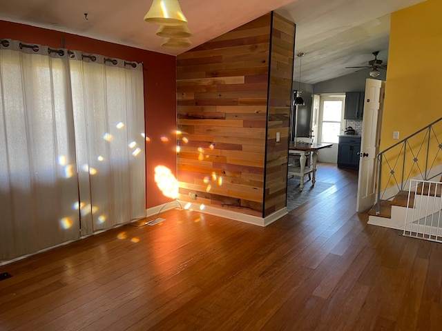 unfurnished room featuring wood walls, vaulted ceiling, and dark wood-type flooring