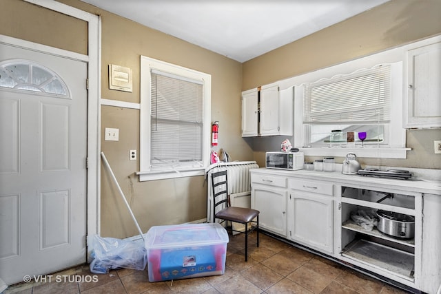 kitchen with tile patterned floors, plenty of natural light, and white cabinetry