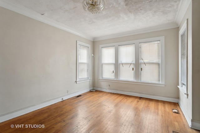 empty room with a textured ceiling, light hardwood / wood-style floors, and ornamental molding