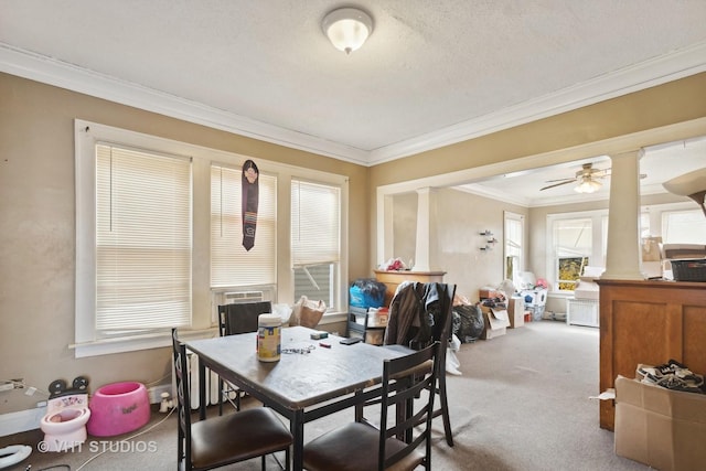 carpeted dining area featuring ceiling fan, crown molding, decorative columns, and a textured ceiling